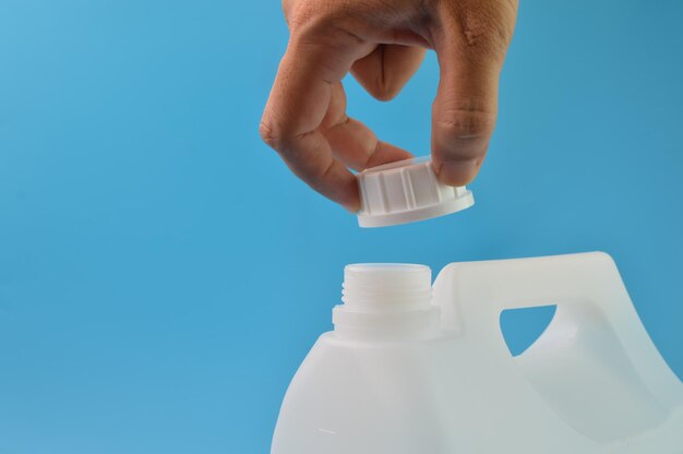 Hand geopende witte gallon kroonkurk geïsoleerd op een blauwe achtergrond