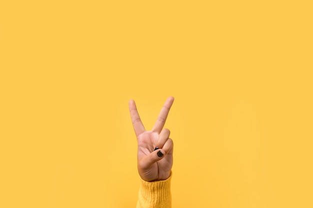 Hand gesture V sign over yellow space