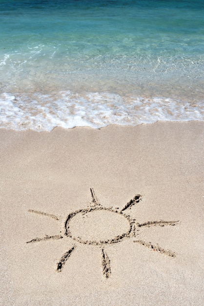 Hand getekend stralende zon op strand zand