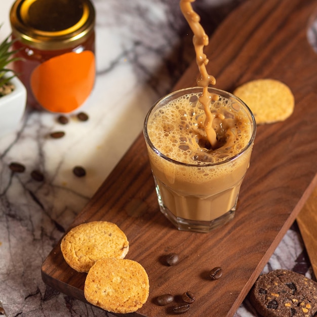 Hand giet koffie in bekerglas