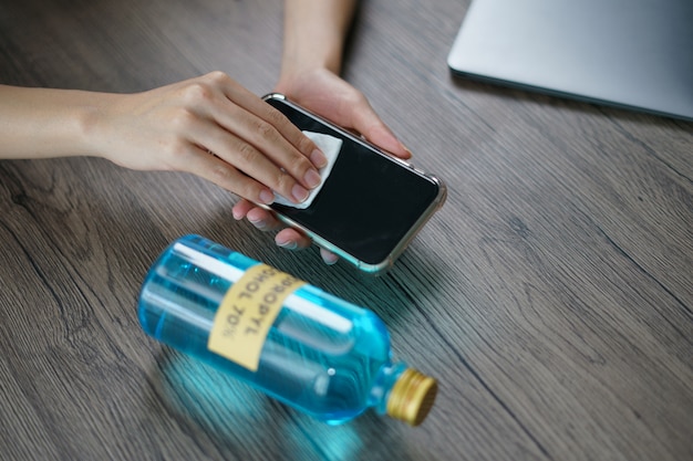 Hand gieten ethylalcohol uit fles in een katoenen stuk voor schone mobiele telefoon