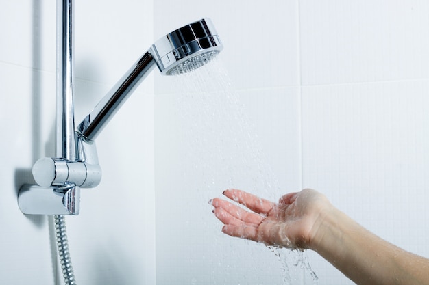 The hand of the girl checks the temperature of the water. splashing