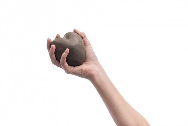 Hand of a girl holding a heart made out of clay.  Symbol for love and valentine days.