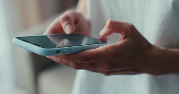 Hand of girl using smartphone in the living room at home typing message Closeup of young women hand