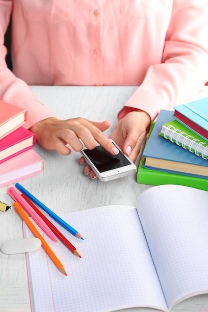 Ragazza di mano con lo smartphone sulla vista da tavolo