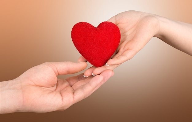 A hand gives a red heart to a hand - blood donation,world blood donor day