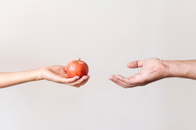 Photo hand giving apple fruit to needy person