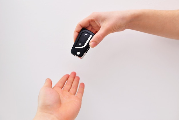 Hand giving car key closeup isolated on background, closeup. Getting driving license.