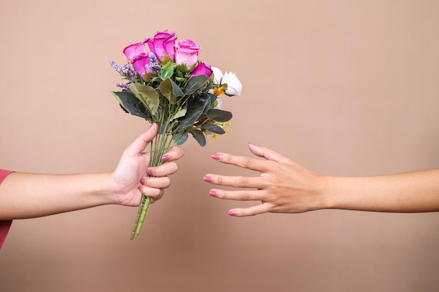 Foto mano che dà un bouquet di fiori e altra mano che lo riceve alla celebrazione della festa della donna