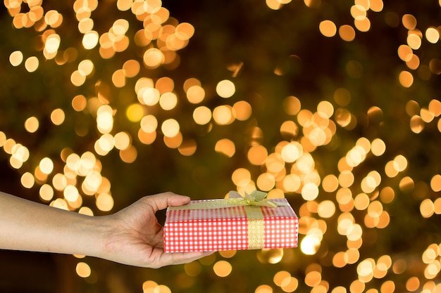 Foto mano che dà il contenitore di regalo rosso su bianco