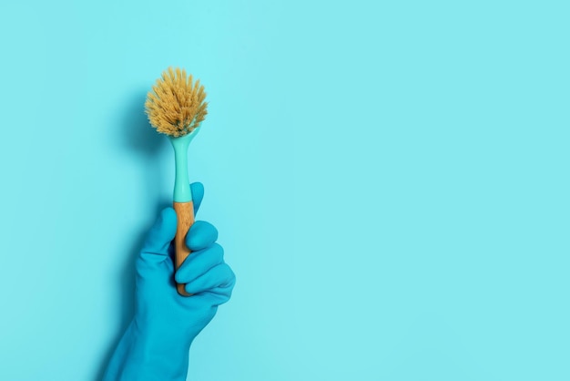 Photo hand in glove holding brush on blue background copy space cleaning house cleaning toilet concept cleaning service concept household chemical cleaning products brushes and supplies