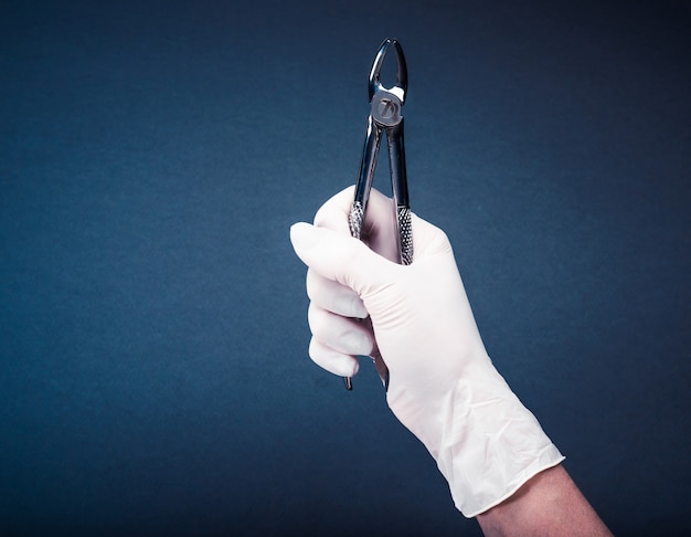 Hand in glove holding medical flatterns on dark blue background