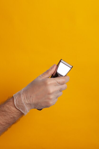 A hand in a glove holds a hair clipper