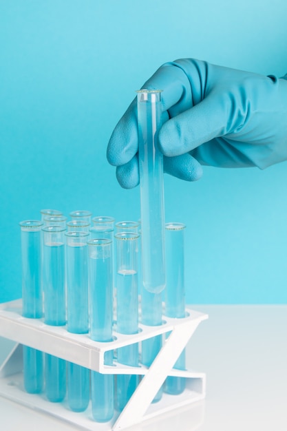 Hand in glove holds test tube with chemical fluid.