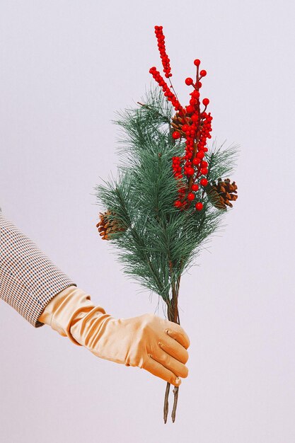 Foto la mano in guanti d'oro tiene il bouquet di abete di natale. moda minimalista. vacanze, capodanno, concetto di inverno.