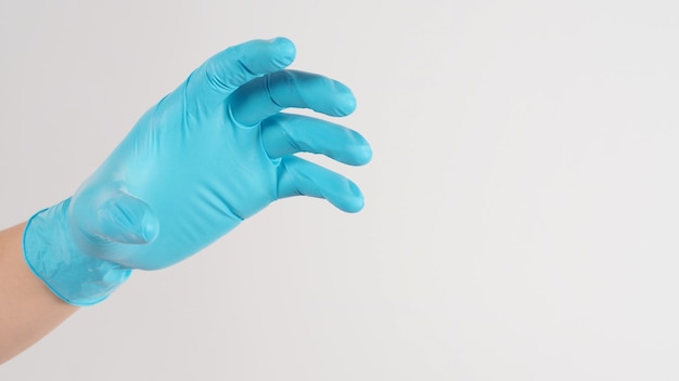 Рука сделать жест и носить синюю медицинскую перчатку на белом фоне.
