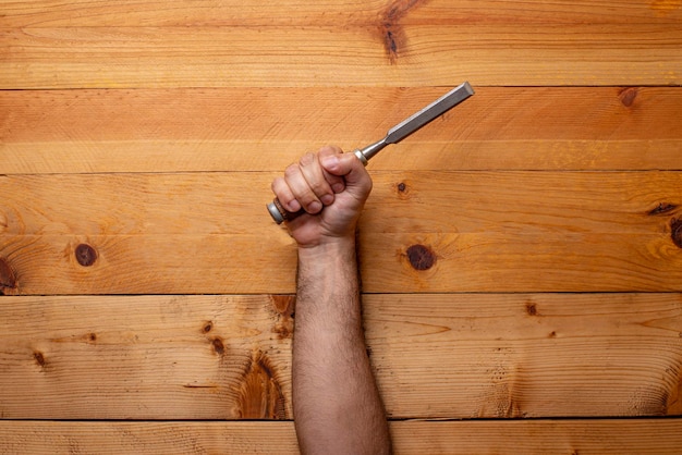 Hand grabbing chisel on light wooden background Labor Day