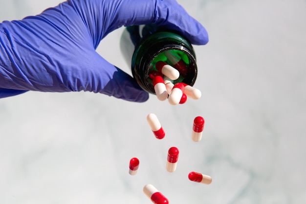 薬でいっぱいの薬局の瓶をつかむ手、ビタミン、薬、薬から落ちるカプセル。健康、ビジネスコンセプトコピースペースの背景