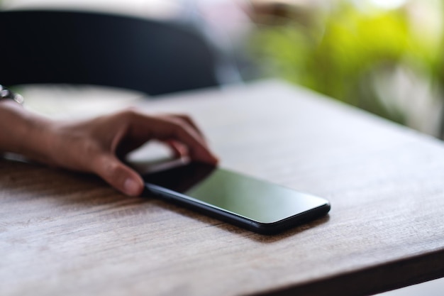 A hand grabbing and picking up mobile phone on the table