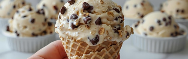 Photo a hand grasps a chocolate chip ice cream cone with granola toppings