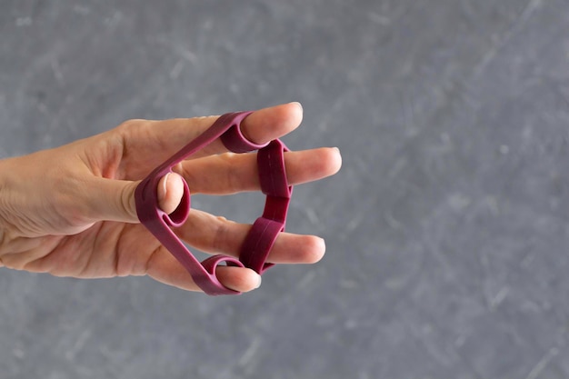 Photo hand grip strengthener in red in the hand of a woman