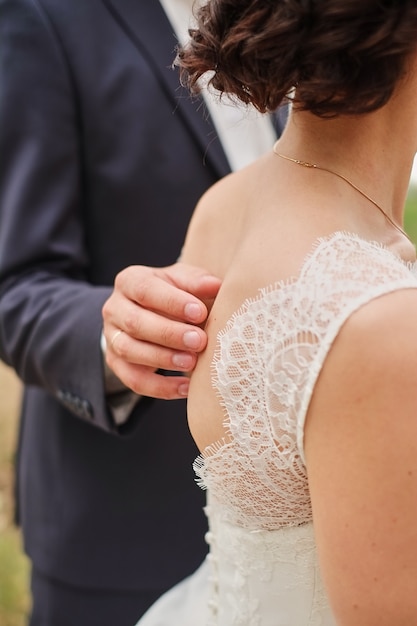 The hand of the groom on the back of the bride.