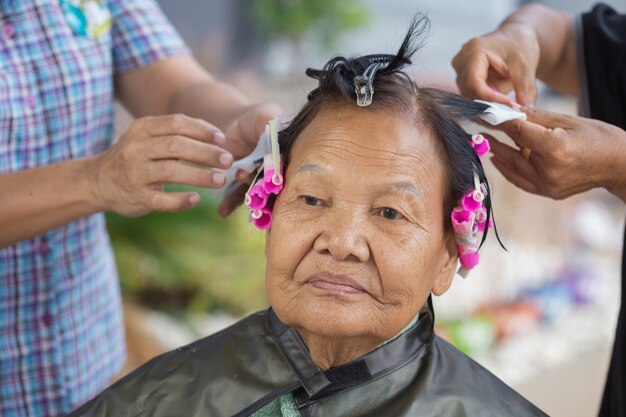 Mano di un parrucchiere facendo una permanente dei capelli di donna senior