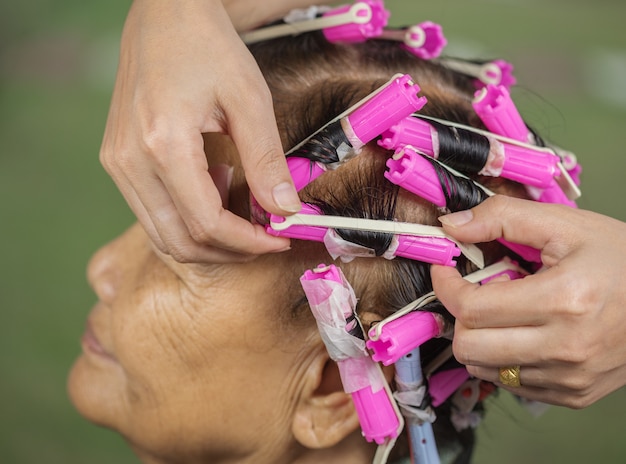 hand of a hairstylist doing a perm rolling hair of senior woman