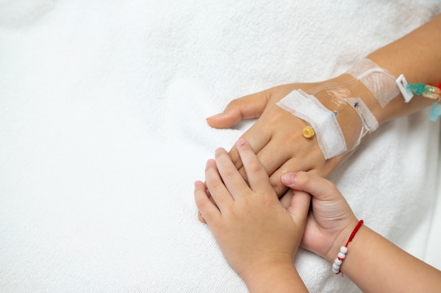 Hand in hand, kid holding hand of old patient in hospital for Encouragement and concern.