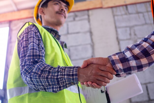 Photo hand in hand between project contractors and customers due to negotiation of expenses and investments, construction and repair of residential buildings.