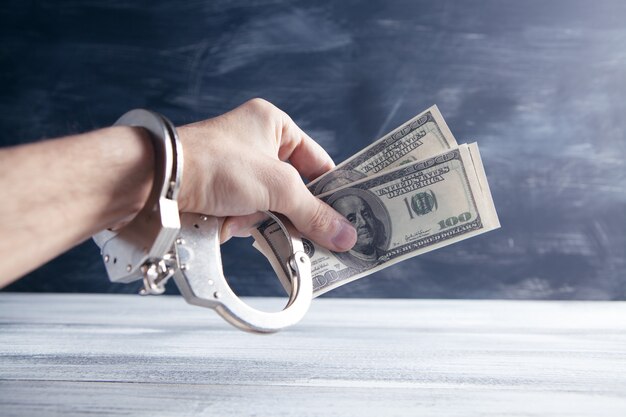 Hand in handcuffs holding money