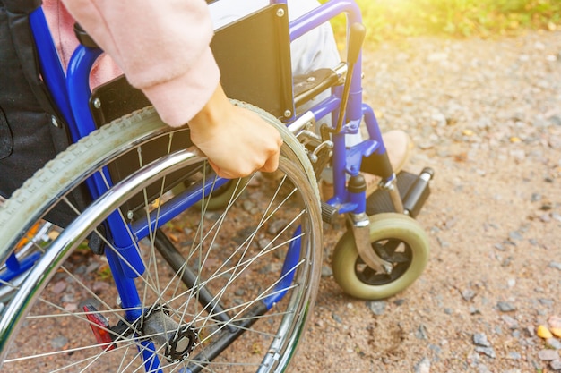 Hand handicap woman in wheelchair wheel on road in hospital park