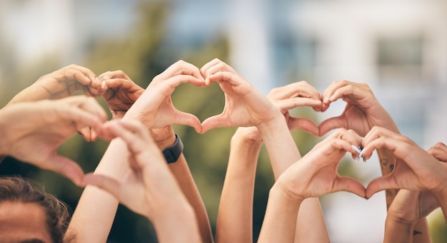 Hand heart and love with a group of people making a sign with their hands outdoor together in the day Crowd freedom and community with man and woman friends doing a gesture to promote health