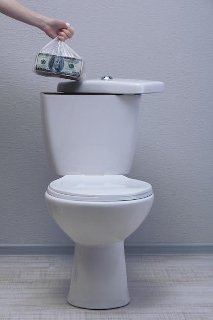 Hand hides money in toilet tank in a bathroom