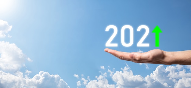 空の背景に2021年のポジティブアイコンを手に持ってください。2021年のコンセプトでビジネスのポジティブな成長を計画します。ビジネスマンの計画と彼のビジネスの肯定的な指標の増加、ビジネスコンセプトの成長。