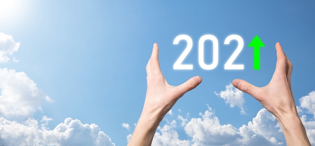 空の背景に2021年のポジティブアイコンを手に持ってください。2021年のコンセプトでビジネスのポジティブな成長を計画します。ビジネスマンの計画と彼のビジネスの肯定的な指標の増加、ビジネスコンセプトの成長。