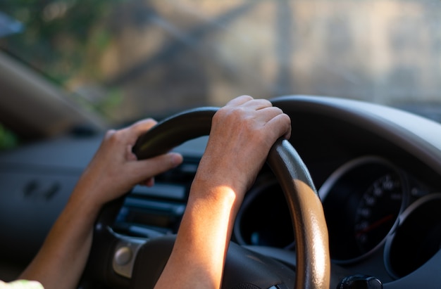 手持ち型車のステアリングホイール。女性は慎重に車を運転します。