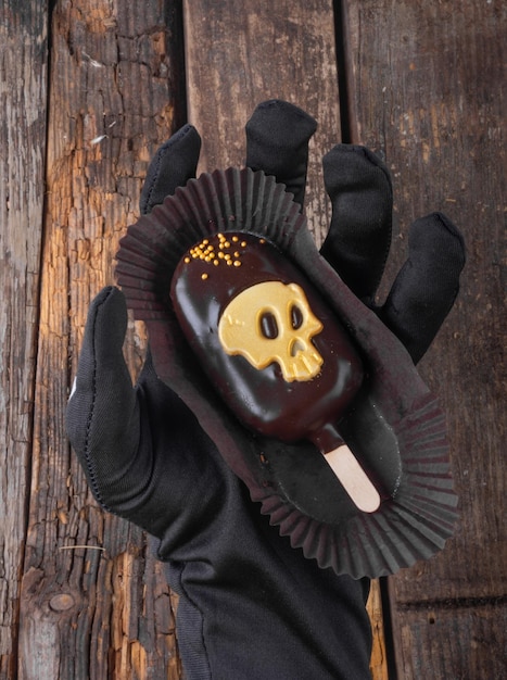 Hand hold chocolate cake ice cream with skull