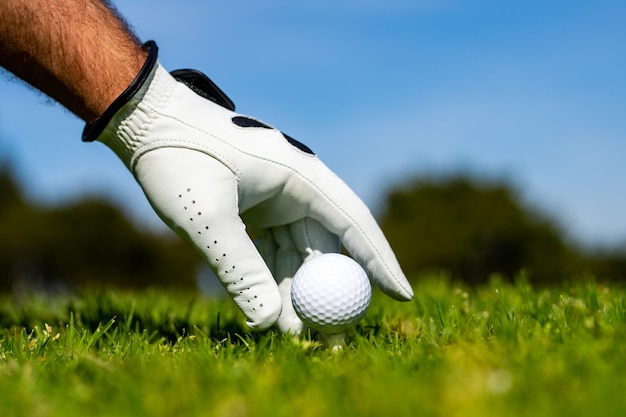 Hand hold golf ball Golfer man with golf glove Hand hold golf ball with tee on course closeup