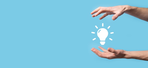 Hand hold light bulb. Holds a glowing idea icon in his hand. With a place for text.The concept of the business idea.Innovation, brainstorming, inspiration and solution concepts.