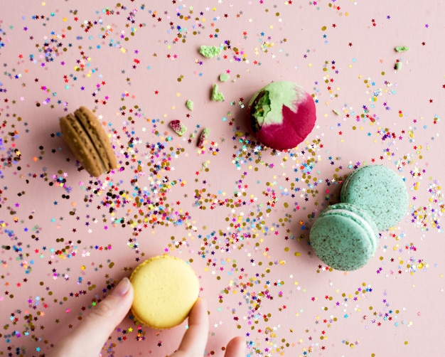 Hand hold macaroon among confetti