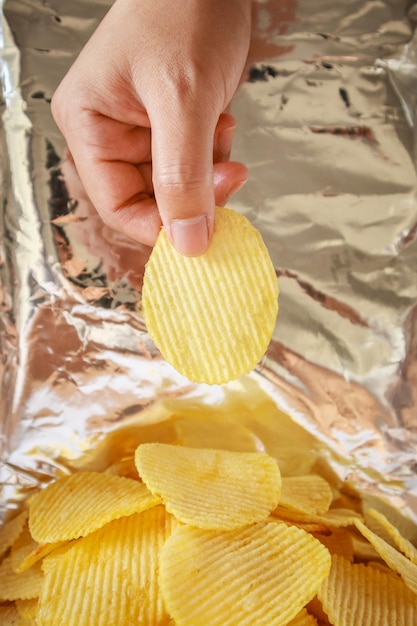 Hand hold potato chips inside snack foil bag