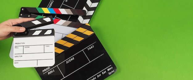 Hand hold small clapper board and 3 clapper boards oR movie slate on the green background floor