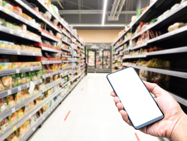 Foto tenere in mano lo schermo bianco dello smartphone sfocatura dello sfondo del centro commerciale