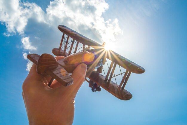 The hand hold a wood plane on the background of the cloud