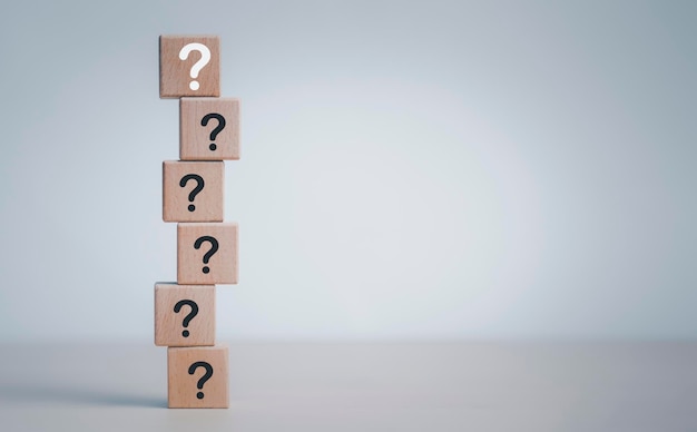 Hand hold Wooden cube block in question mark mean what on cement table background, column of wooden blocks with question sign mark. copy space,FAQ frequently asked questions, Answer, Information