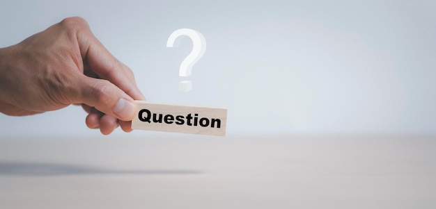 Hand hold Wooden cube block in question mark mean what on cement table background, column of wooden blocks with question sign mark. copy space,FAQ frequently asked questions, Answer, Information