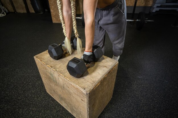 Hand holdind dumbbells on wooden box in modern gym functional
training