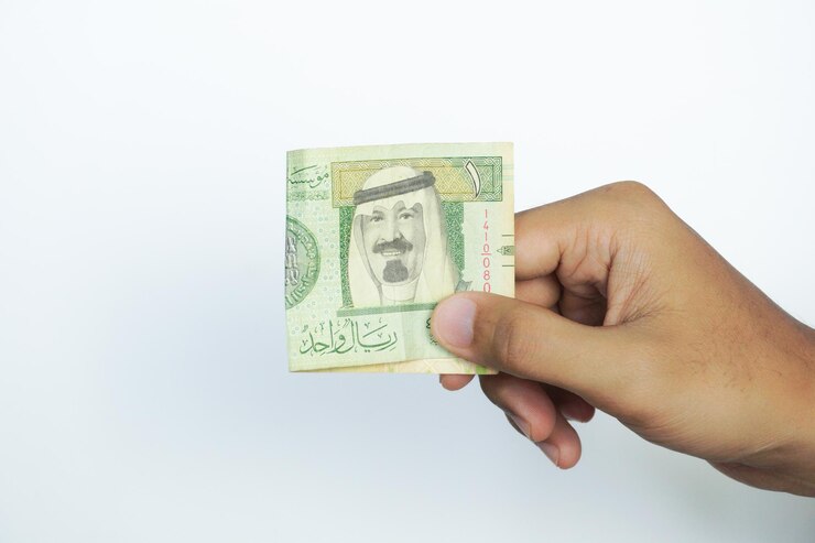 Photo hand holding 1 riyal saudi arabia money on a white background