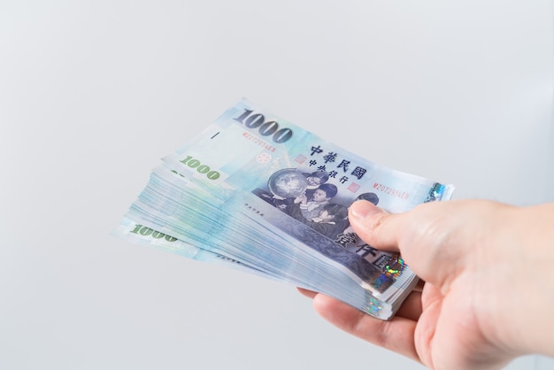 A hand holding a 1000 New Taiwan Dollar bill.